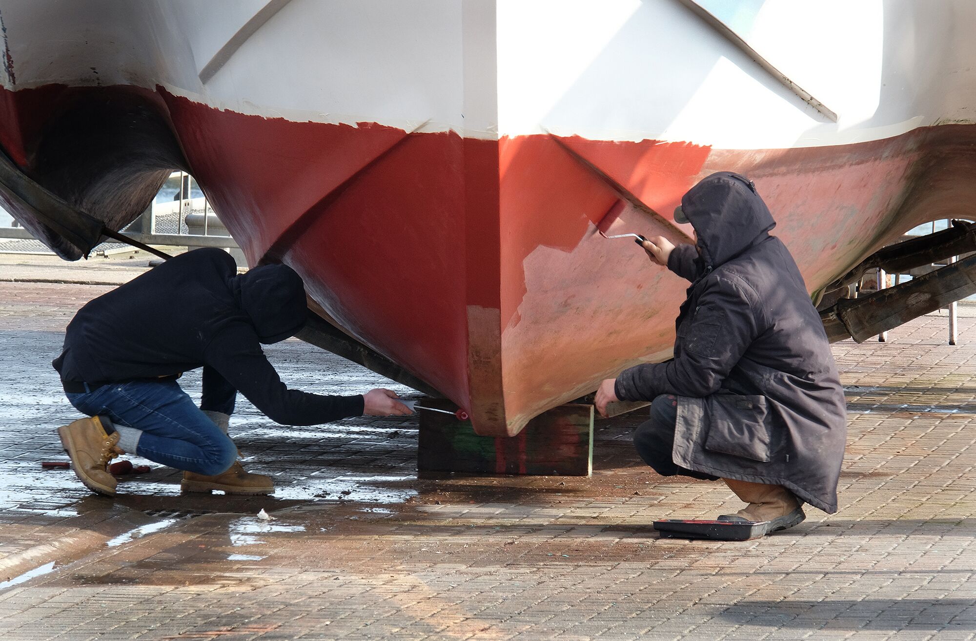 Two people painting a boat bottom