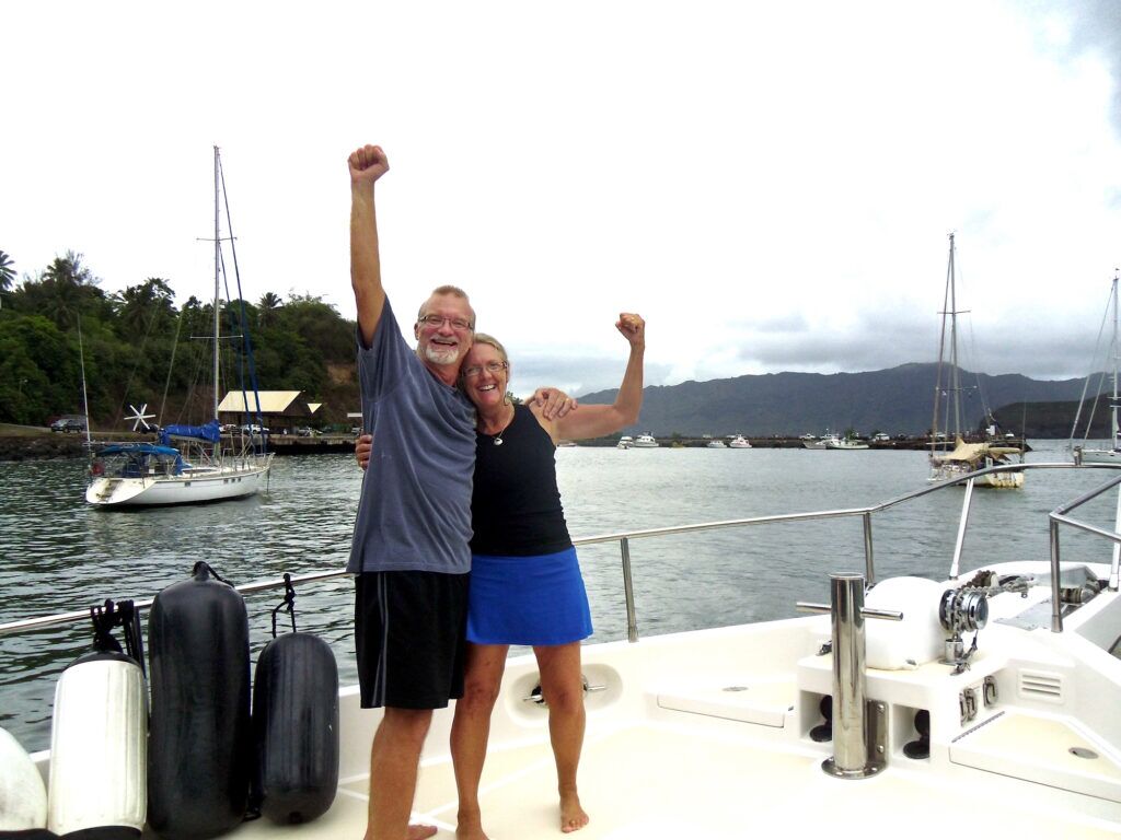 A couple with hands raised on a boat bow